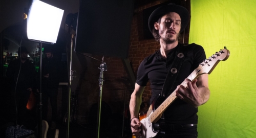 Ein Musiker wird vor Greenscreen aufgenommen, um ihn in der Postproduktion in eine andere Szenerie versetzen zu können.